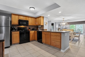 A modern kitchen with wooden cabinets, stainless steel appliances, and a large island.
