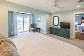 Un dormitorio con una cama grande, un aparador, un televisor y una silla.