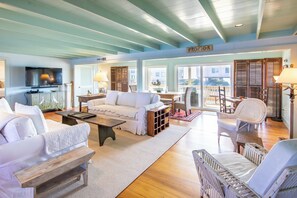 A spacious living room with a television, seating area, and a view to the outside.