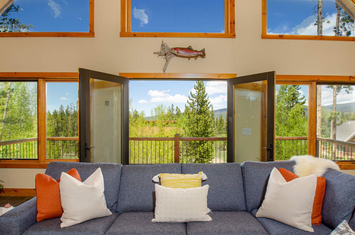 A room with a gray sofa, wooden beams, and a large fish decoration.