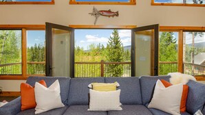 A room with a gray sofa, wooden beams, and a large fish decoration.