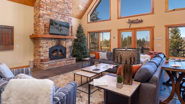A spacious living room with a stone fireplace, large windows, and a cozy seating area.