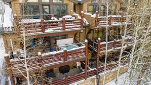 Ein mehrstöckiges Blockhaus mit Balkon und sichtbarer Außenbereichs-Sitzgruppe.
