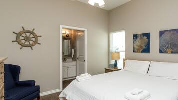 A clean, well-lit bedroom with a large bed, a ceiling fan, and artwork on the walls.