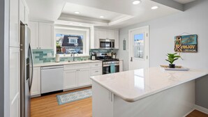 Una cocina moderna con armarios blancos, una isla central, un microondas y una estufa.