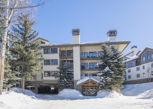 Ein mehrstöckiges Hotel mit Balkonen, einem verschneiten Eingangsbereich und einem Ski-Lodge-Bereich.