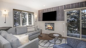 A modern living room with a fireplace, grey sofas, a coffee table, and large windows with a snowy view. - Ski-In and Out in Beaver Creek Village Condo w/ Balcony, Hot Tub, Free Shuttle  (Beaver Creek)
