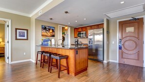 Eine moderne Küche mit Holzausstattung, einem Edelstahlkühlschrank und einer Bar mit Hockern.