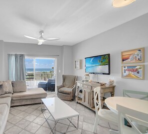 Relax in this ocean-view living room with a flat-screen TV, beige sofa, and dining table.
