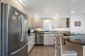 Une cuisine moderne dotée d’appareils électroménagers en acier inoxydable, de meubles de couleur beige et d’un plan de travail en granit.