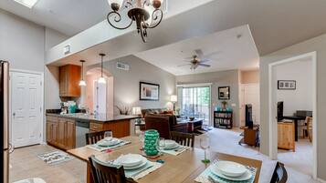 A spacious kitchen with wooden cabinets, a dining table set for four, and a ceiling fan.