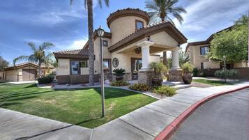 A residential house with a curved roof, a stone facade, and a well-maintained lawn.