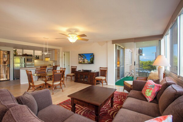 A spacious living area with a dining table, sofas, and a TV.
