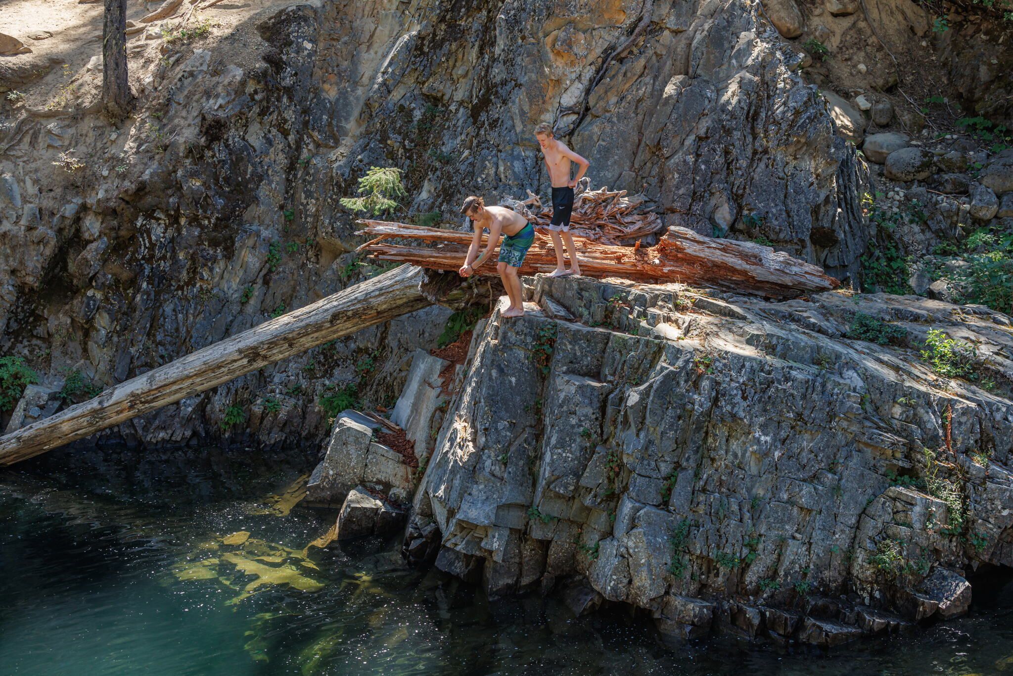 A rocky cliff with two individuals standing on a ledge.