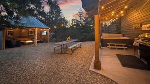 A rustic outdoor patio with a wooden deck, a barbecue grill, and a hot tub. - Unique Covered Silo Lounge | Fire-Pit Gatherings+ EV Ready & 1PM Check-IN/OUT (ronald)