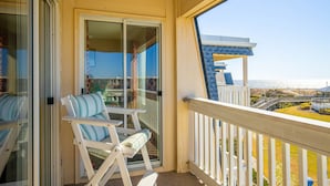 Un balcon donnant sur la plage et un bâtiment avec un toit bleu.