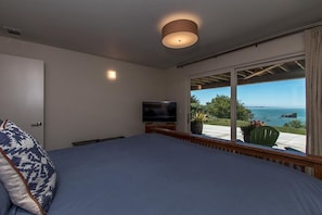 Un dormitorio con una cama grande, televisión y vista al océano.