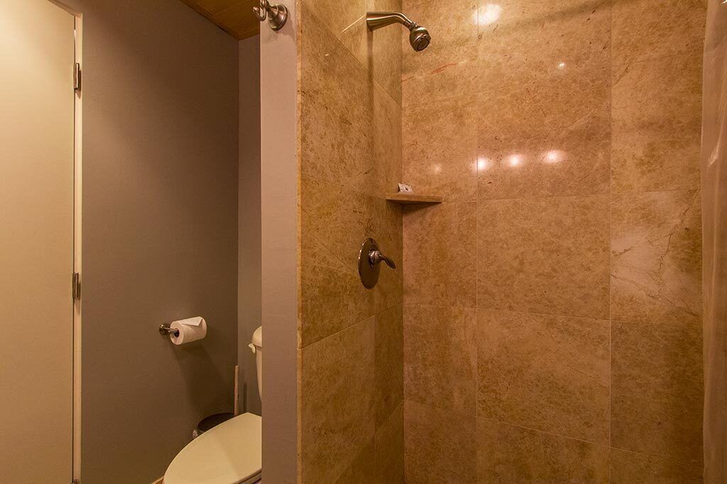A bathroom with a toilet, a shower with a glass door, and a towel rack.