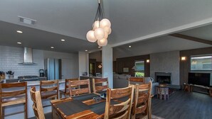 A modern kitchen with a dining area, wooden chairs, and a chandelier. - Treasure Cove-Hot Tub, Ocean Views & Near Beach (Trinidad)
