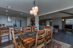 Una cocina moderna con comedor, sillas de madera y una araña.