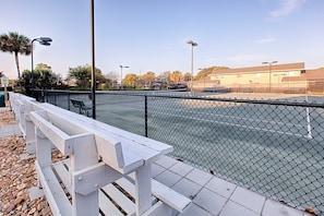 Enjoy a game of tennis on the outdoor court surrounded by lush surroundings and comfortable seating.