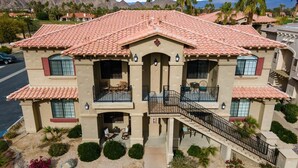 A two-story building with a red-tiled roof, balconies, and a staircase leading to the entrance.