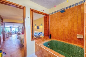 A bathroom with a green-tiled bathtub, wooden door frames, and a tiled shower area.