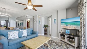 Ein Wohnzimmer mit blauem Sofa, Holztisch und Fernseher, der 'Legacy Vacations' anzeigt.