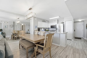 Une cuisine moderne avec des meubles blancs, un îlot central et un coin repas doté de meubles en bois.