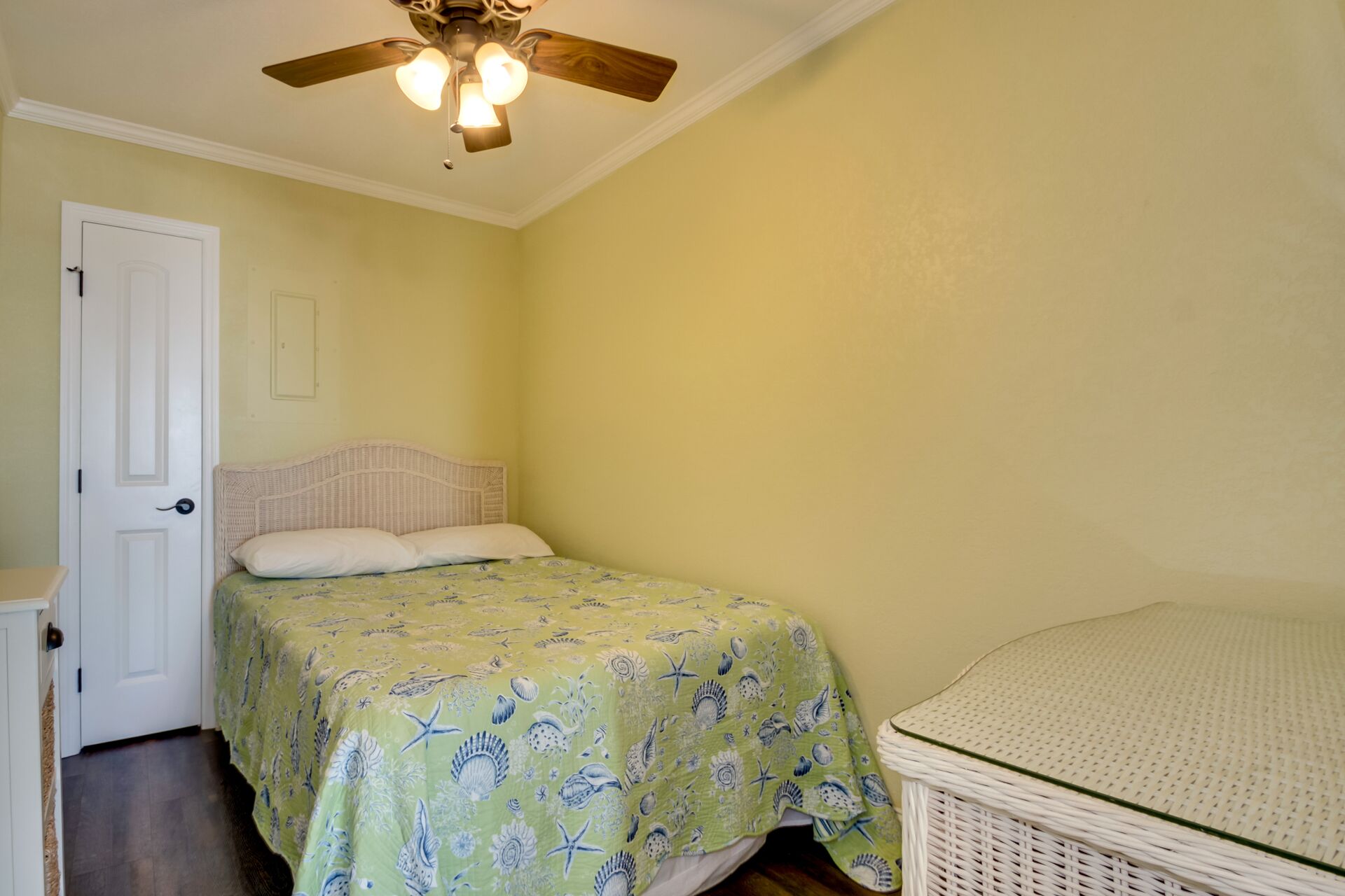 A bedroom with a bed, a nightstand, a white door, and a ceiling fan.