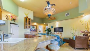 A spacious kitchen with a granite countertop, a built-in sink, and a ceiling fan.