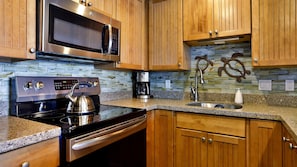 Fully equipped kitchen with stainless steel appliances, wooden cabinetry, and granite countertop.