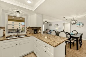 A kitchen with white cabinets, granite countertops, and a dining area with a table and chairs.