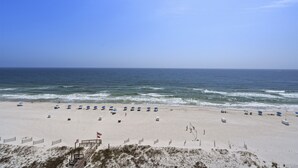 A beach with umbrellas and beach chairs, a lifeguard tower, and a fence.