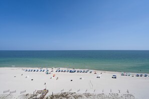 A beach with a clear sky, a sandy shore, and several umbrellas.