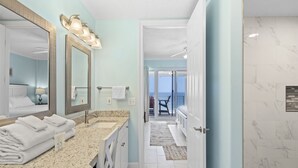 A bathroom with a large mirror, two sinks, and a shower area.