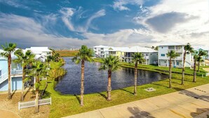 A waterfront residential area with houses, a canal, and palm trees. - Island Breeze Home, Dual Pools & Private Decks (Port Aransas)