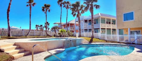 A swimming pool with steps leading into it, surrounded by palm trees and a white fence.