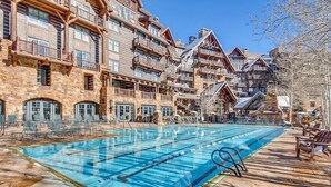 Ett poolområde med en klarblå pool, solstolar och en terrass av sten.