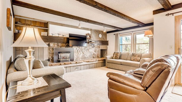 A cozy living room with a fireplace, leather sofa, and a coffee table. - Perfect Downtown Retreat with ALL NEW APPLIANCES AS OF FALL 2025! (Breckenridge)
