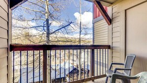 A balcony with a view of a mountainous landscape, a metal railing, and a plastic chair. - Perfect Downtown Retreat with ALL NEW APPLIANCES AS OF FALL 2025! (Breckenridge)