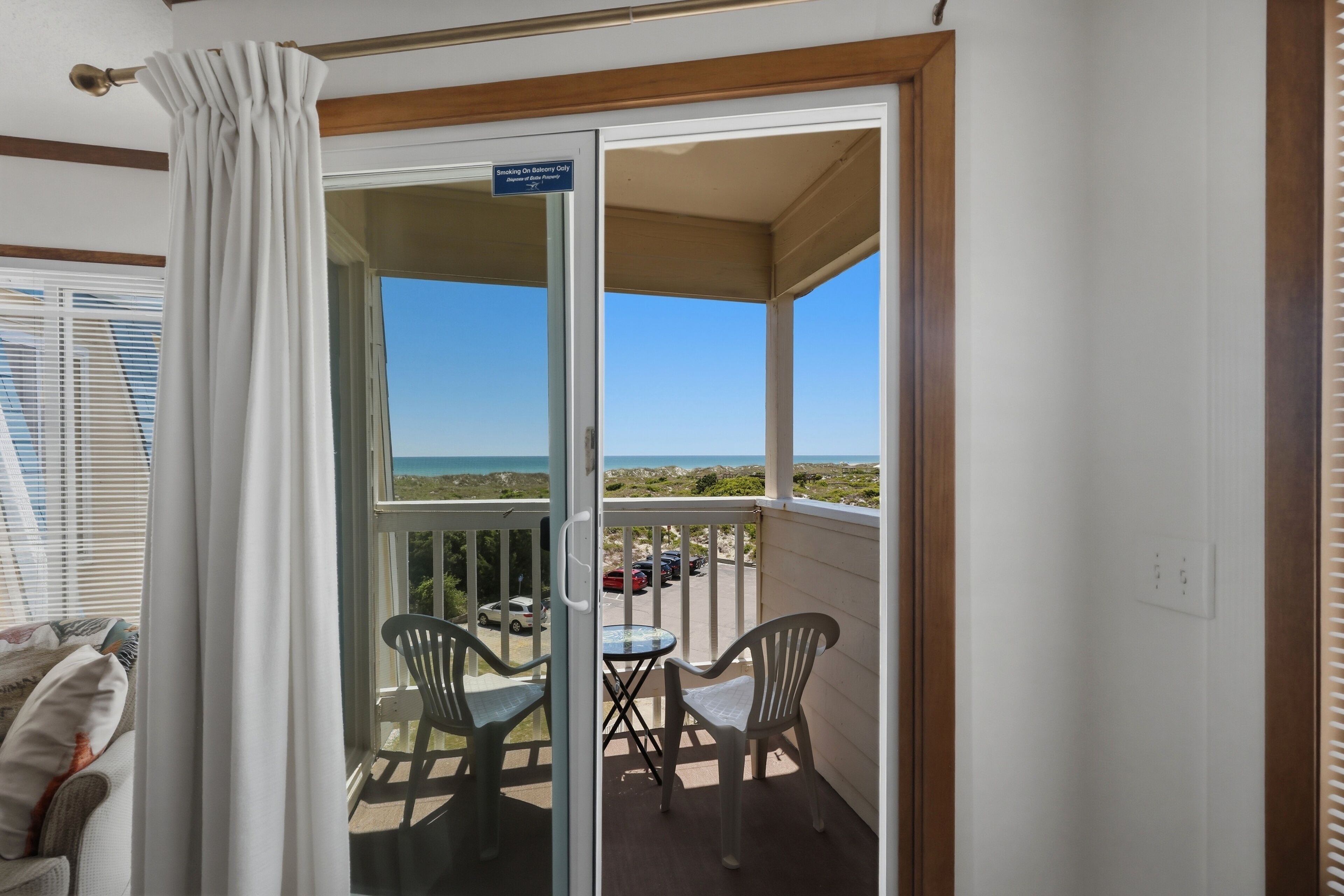 Un balcone con vista sul mare, un cartello che indica che è consentito fumare e due sedie.