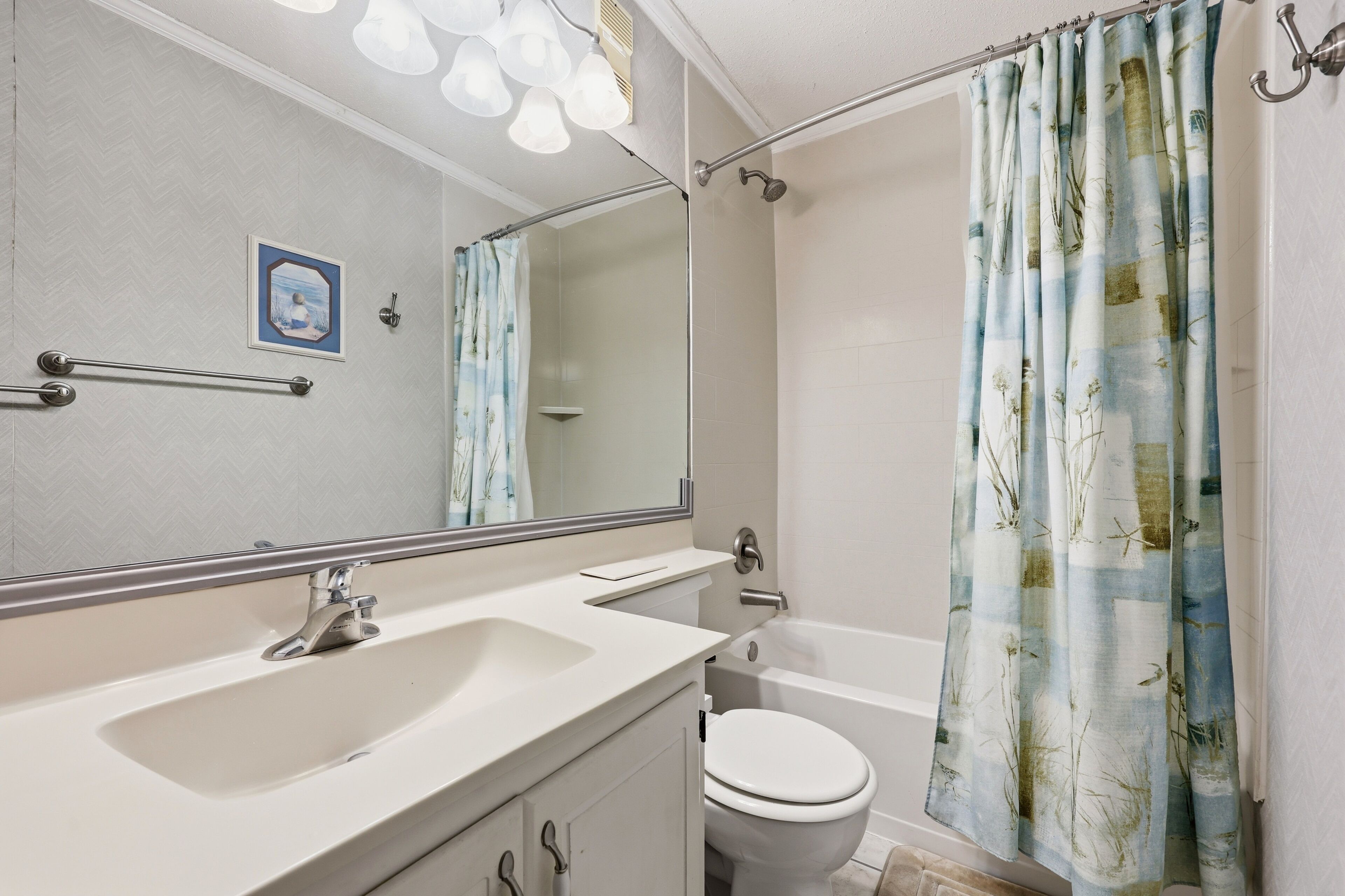 Een badkamer met een wastafel, spiegel, toilet en douchegordijn.