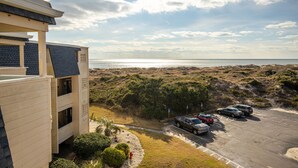 A beachfront property with a parking area and a view of the ocean.