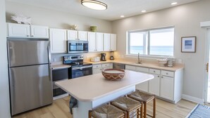 A modern kitchen with white cabinets, stainless steel appliances, and a large island with bar stools. - Gulf Front, Gorgeous Panoramic Gulf Views, Large Deck, Dune Allen Beach (Santa Rosa Beach)
