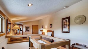 Ein Hotelzimmer mit einem Bettgestell aus Holz, einer Deckenleuchte und gerahmten Bildern an den Wänden.