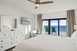 Enjoy a comfortable stay with a large bed, ceiling fan, and ocean views through the sliding glass door.