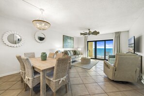 Relax in the spacious living room with a dining area, featuring a round dining table, comfortable sofa, and reclining chair.