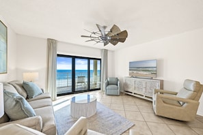 Relax in this stylish living room with a panoramic ocean view, featuring a comfortable sofa set, coffee table, and armchair.