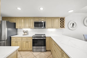 Enjoy cooking in this well-equipped kitchen with a refrigerator, microwave, double oven, and light wood cabinetry.